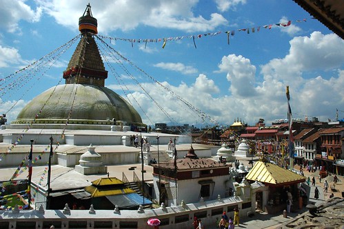 Sur offering on the steps of the Boudha Stupa, as seen from the northeast view of the shrine and candle offering rooms, on a sunny day with puffy clouds, Boudha, Kathmandu, Nepal by Wonderlane
