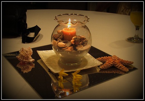 A simple tall glass candleholder surrounded by smaller glass tea light 