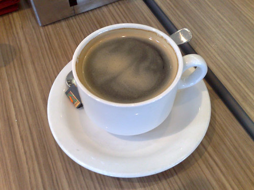 White Coffee Cup On White Saucer With Silver Spoon On Wood Table