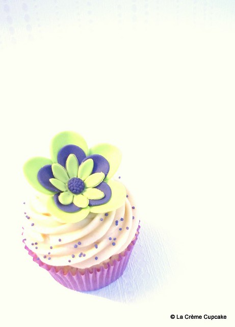 Vanilla cupcake decorated with lime green and purple flowers