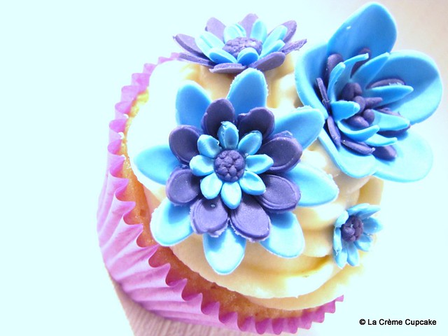 Vanilla cupcake decorated with striking electric blue and purple flowers