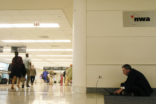 a man charging a device at an airport