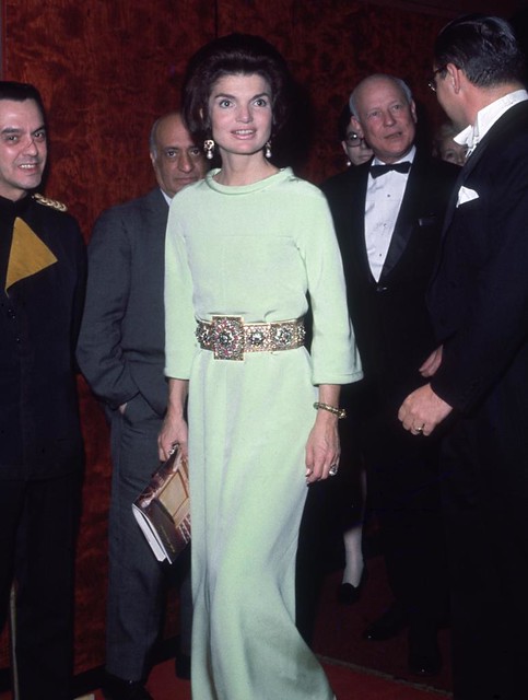 Jacqueline Kennedy stands and holds a program while attending the 