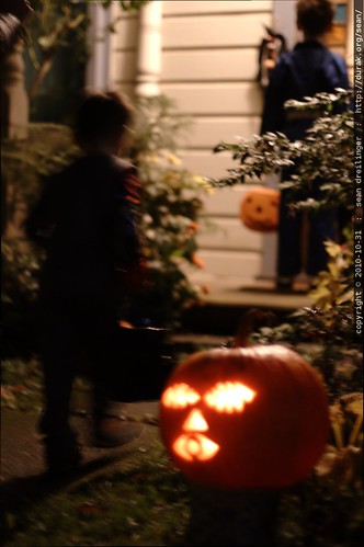 arriving on another halloween doorstep, greeted by a lit jack o lantern