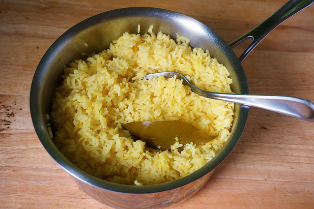 Just-cooked bay leaf rice fills a medium saucepan, with the fork that fluffed it still resting against the lip.