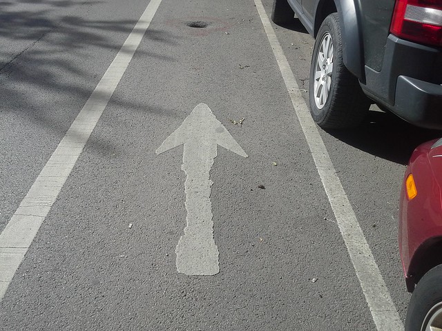 Perspective of bike lane with hole and arrow leading right to it