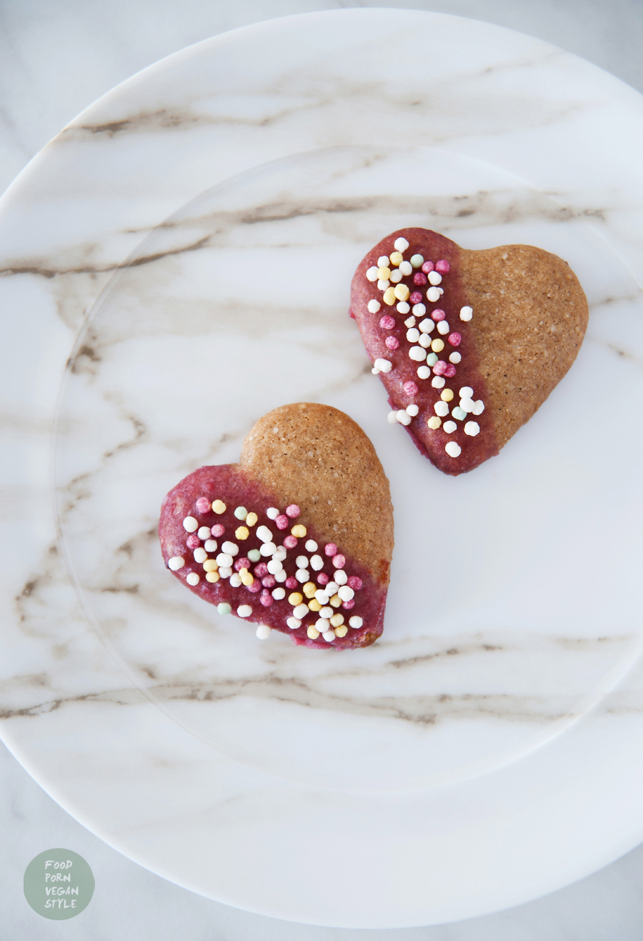 Vegan almond-chestnut cookies 'hearts' with pink icing and colorful sprinkles