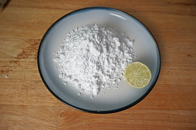 A miniature mountain of powdered sugar on a round plate, with half a lime sitting next to it, cut side glistening in the light.