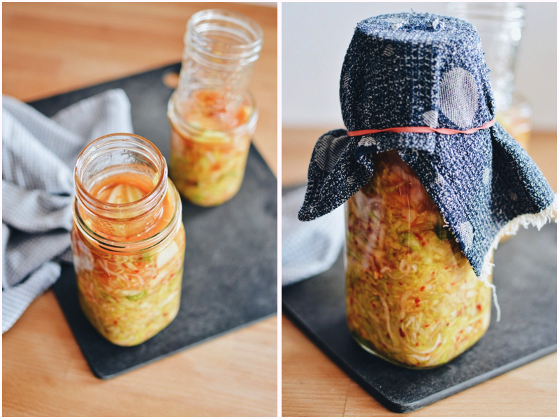 Kimchi kraut weighted down with small jar and covered with cloth.