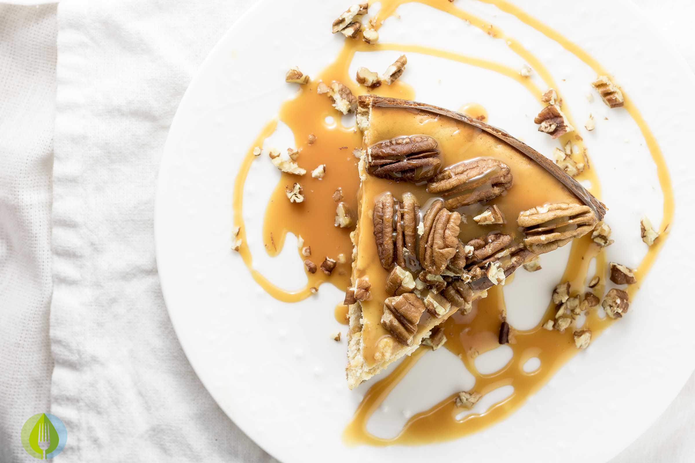 one piece of pecan chesecake on a plate with caramel sauce and pecans
