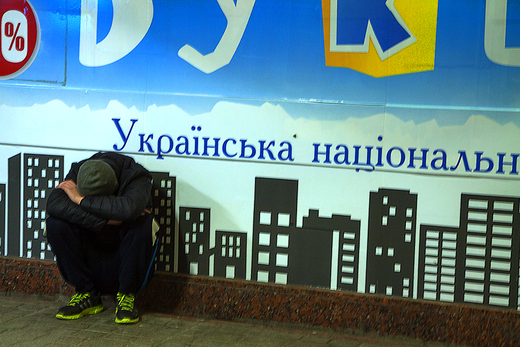 Young squatting man with head down--Kiev