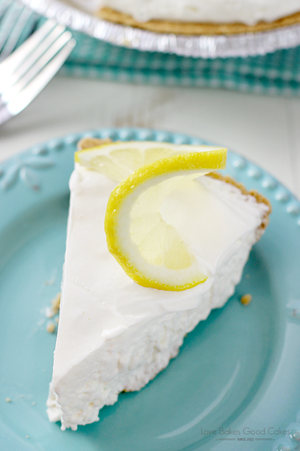 Frozen Lemonade Pie on a blue plate with a slice of lemon and a fork.