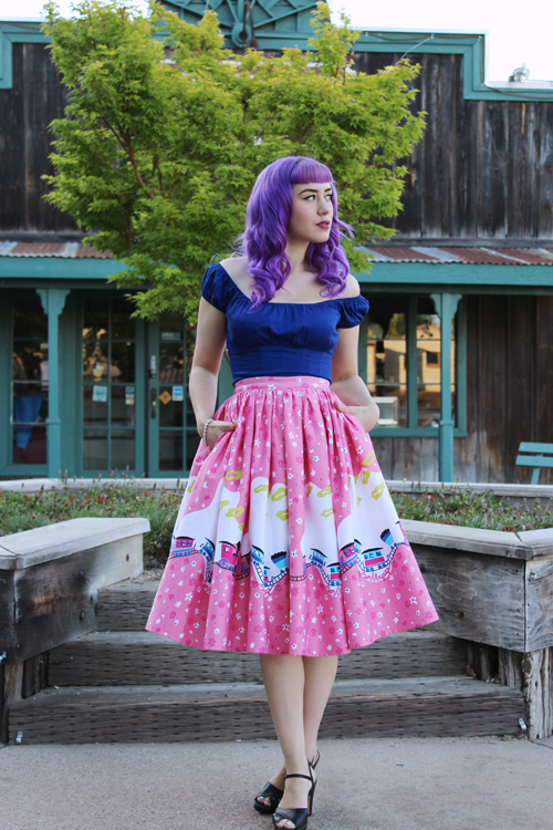 Pinup Girl Clothing Pinup Couture Peasant Top in Dark Royal Blue Jenny Skirt in Mary Blair Pink Train Border Print