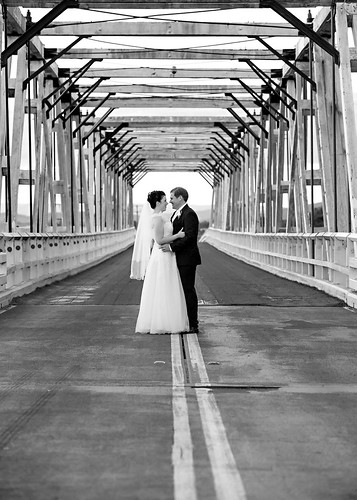 The bride and groom embracing on a bridge.
