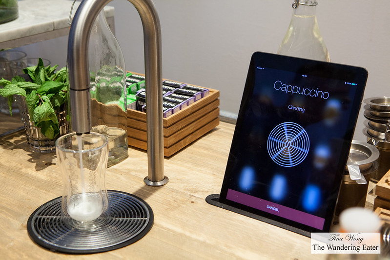 A futuristic looking cappuccino maker with a control of an iPad