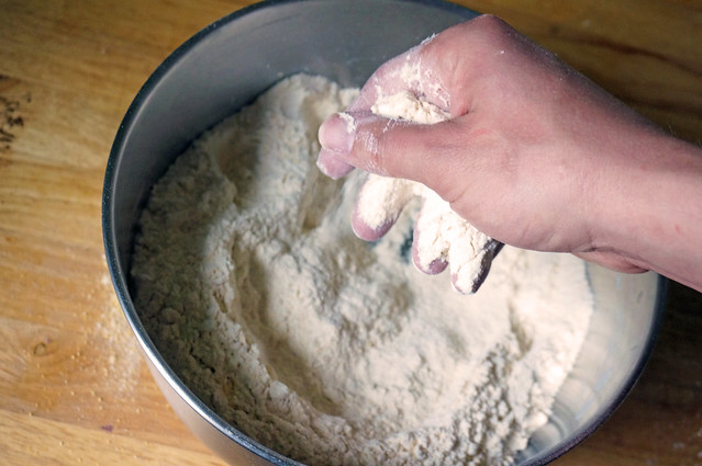 A hand (my hand, I should say) rubs flour into a metal bowl: biscuits in the making.