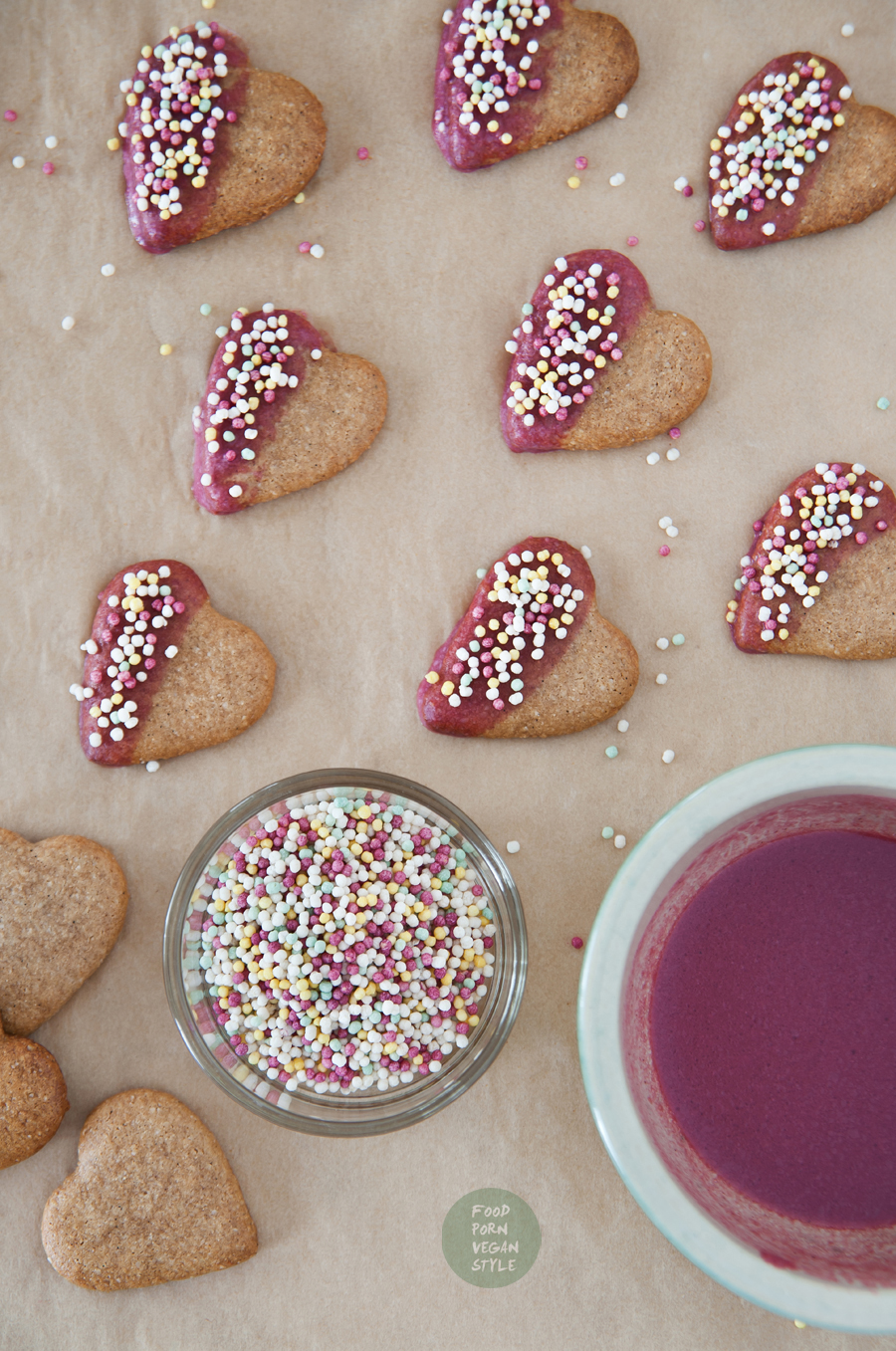 Vegan almond-chestnut cookies 'hearts' with pink icing and colorful sprinkles