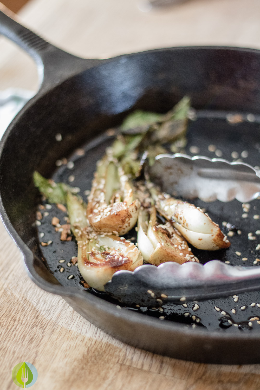 sauted baby bok choy with chili and sesame seeds in a cast iron skillet