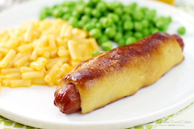 Easy Pretzel Dog on a white plate with macaroni and cheese and green peas.