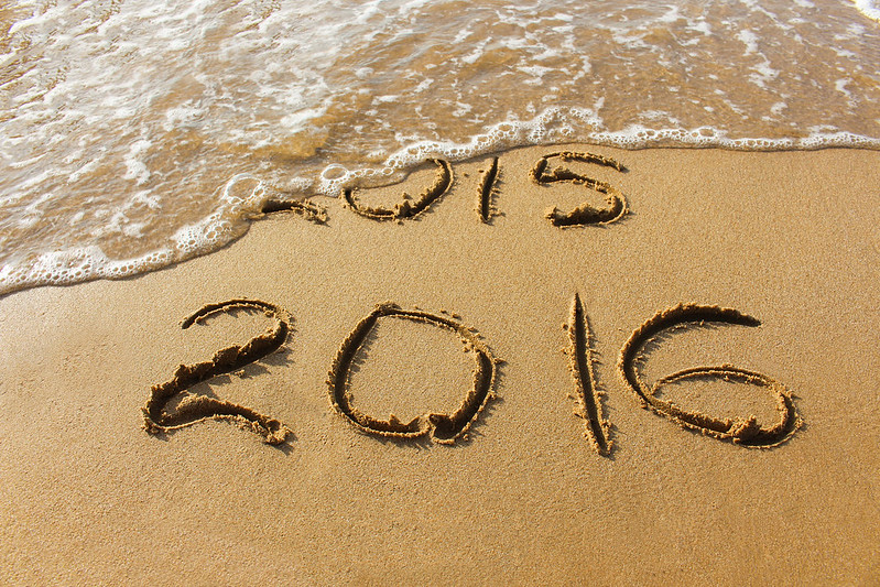 2015 and 2016 year written on sandy beach sea. Wave washes away 2015.