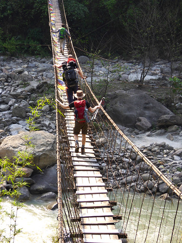 Trekkers making their way across a medium length swingbridge in Nepal's  Annapurna region