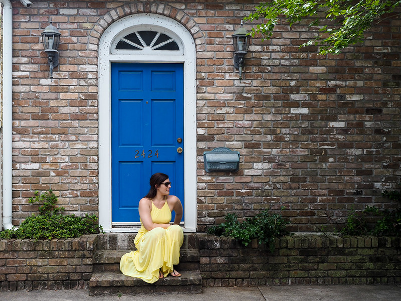 Girl in yellow dress sitting in front of a blue door in New Orleans Garden District