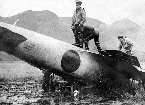 U.S. military personnel inspect a Japanese Zero aircraft piloted by Tadayoshi Koga that crashed on Akutan Island after bombing Dutch Harbor on June 4, 1942. The Zero was later shipped to the United States and put into flying condition for intelligence purposes. Koga was killed in the crash. / 1942年6月4日のダッチハーバー攻撃後にアクタン島に不時着した零戦（搭乗員は古賀忠義一飛曹、不時着時に死亡）を検分するアメリカ軍。機体はアメリカ本土に送られ、零戦研究に利用された. Photo taken by Navy Photographer's Mate Arthur W. Bauman.
