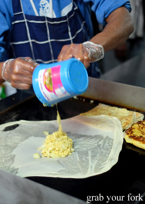 Adding egg and oinon to paratha roti to make martabak at Lakemba Ramadan Food Festival 2018 on Haldon Street