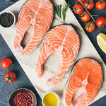 Fresh salmon steaks, herbs, olive oil and cooking ingredients on marble background