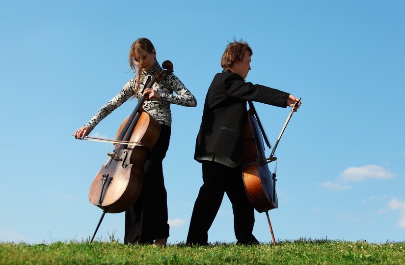 two cellists playing outdoors facing in opposite directions