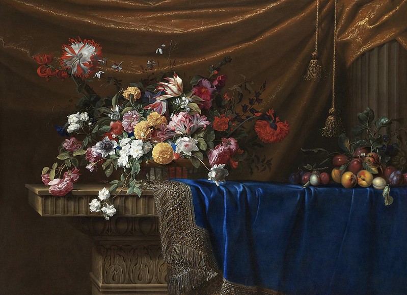 Jean-Michel Picart - A still life of a basket of flowers and a mound of fruit on a sculpted stone table, partly covered with a blue velvet, gold-and-silver fringed cloth with drapery and a stone column in the background