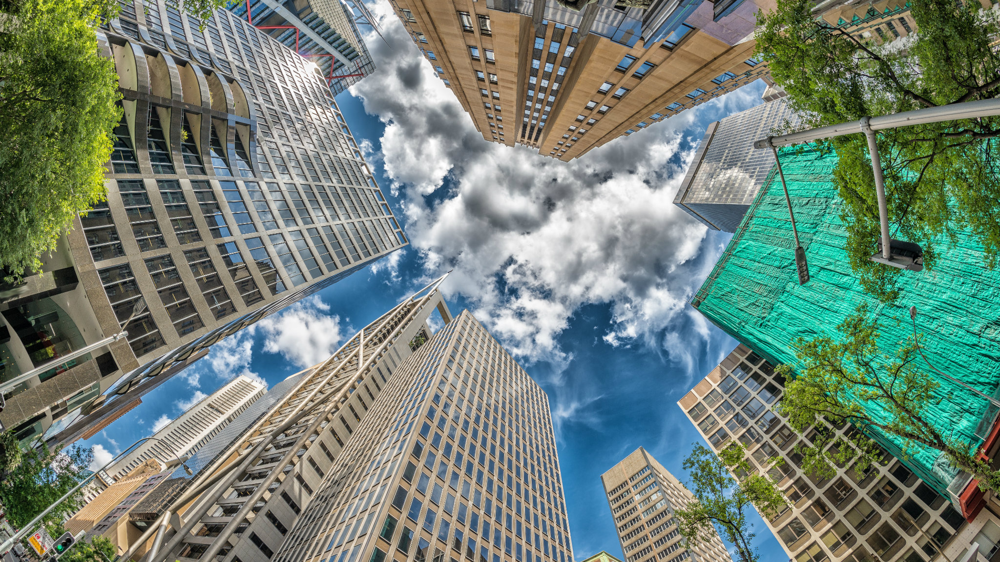 A worm's eye view of some skyscrapers reaching into a blue sky