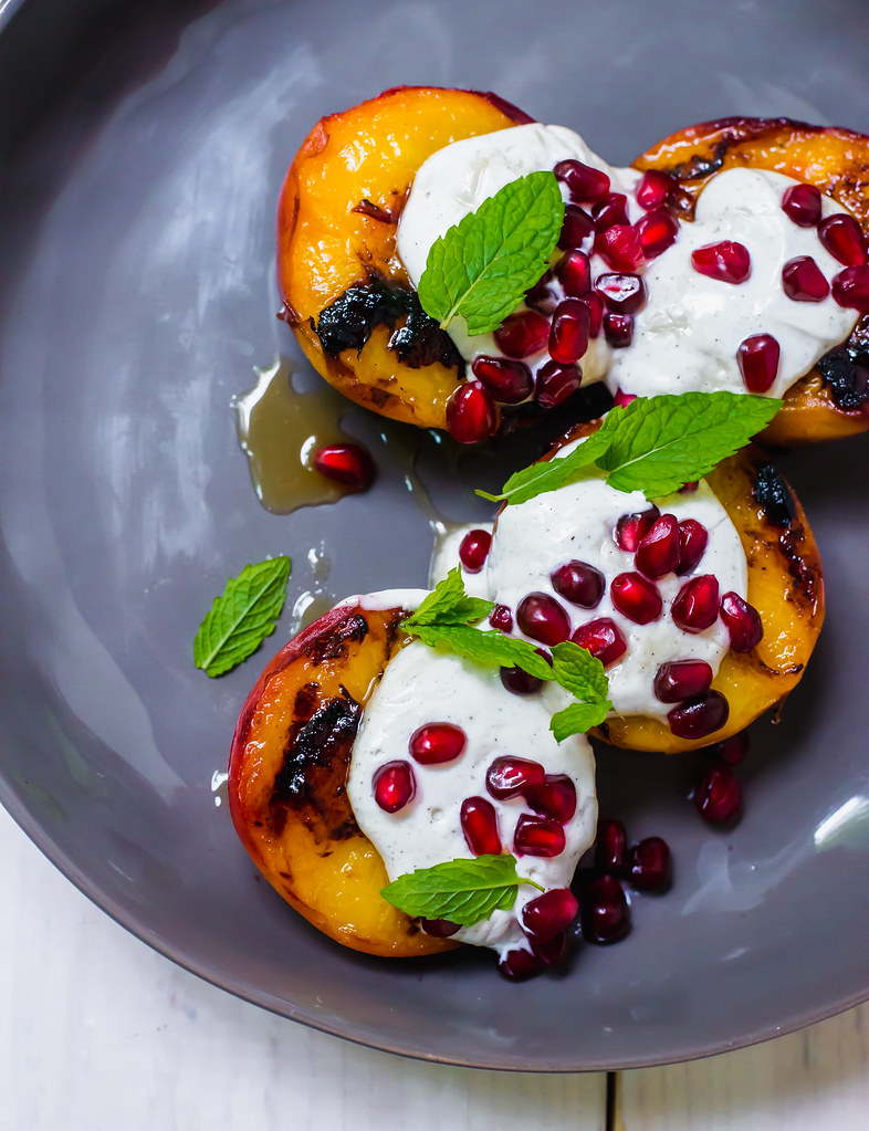 This simple stone fruit dessert recipe is the epitome of summer. Sweet grilled peaches are topped with with tangy vanilla speckled labneh and finished with honey and pomegranate seeds. 