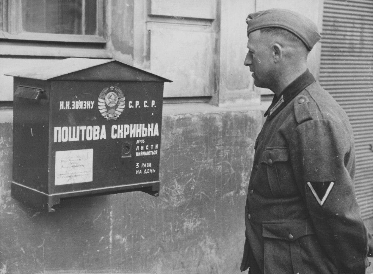 Немецкий солдат смотрит на почтовый ящик на стене дома во Львове, июнь - июль 1941 года.