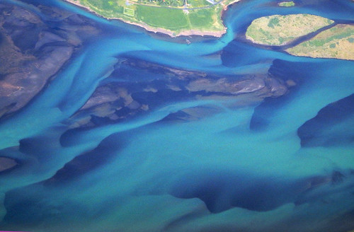 Aerial shot of a turquoise river in Iceland from a commercial Icelandair flight