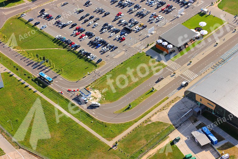 Parking samochodowy i fragment hali lotniska w Modlinie.