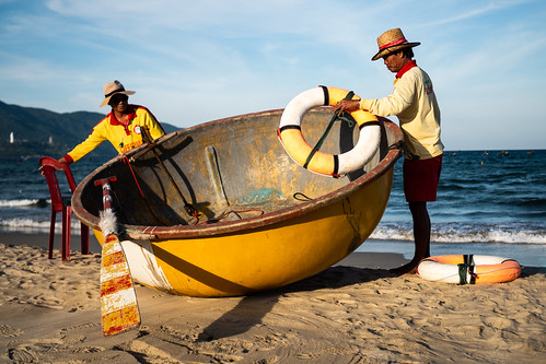 danang vietnam asia beach basket boat men coast coastguard man lifeguard sea ocean yellow orange sunset sand blue hat chair