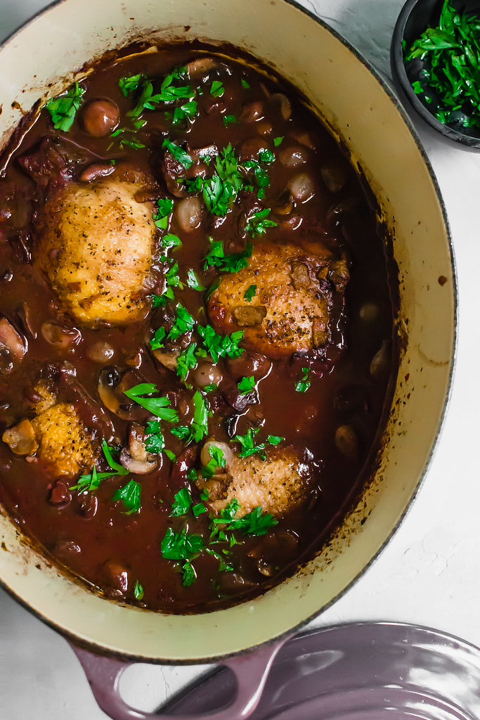 Step by step instructions for Julia Child's Coq Au Vin, with stewed chicken in a rich buttery red wine sauce with sauteed mushrooms and pearl onions.