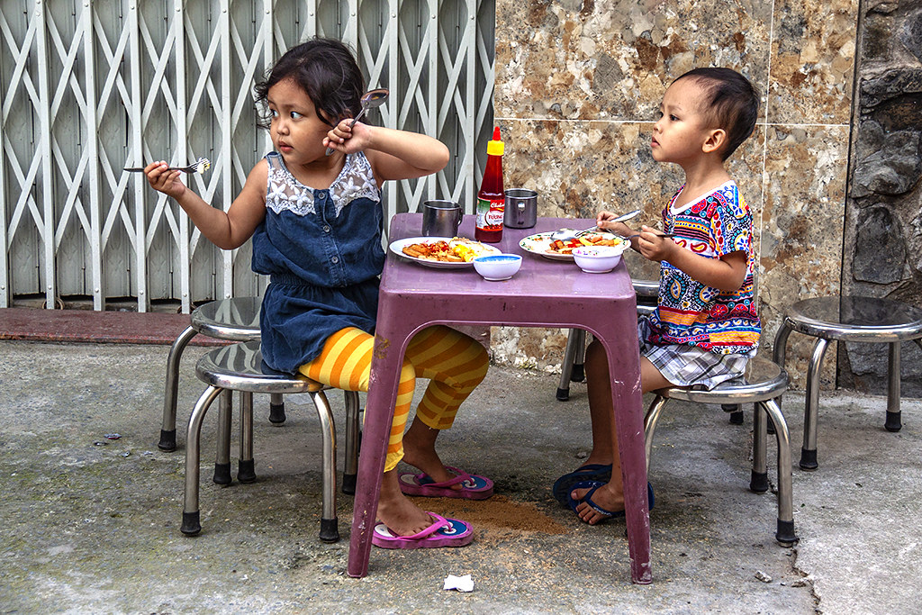 Kids eating breakfast in an alley--Saigon