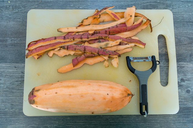 Peeled Sweetpotato with peeler and skin on cutting board