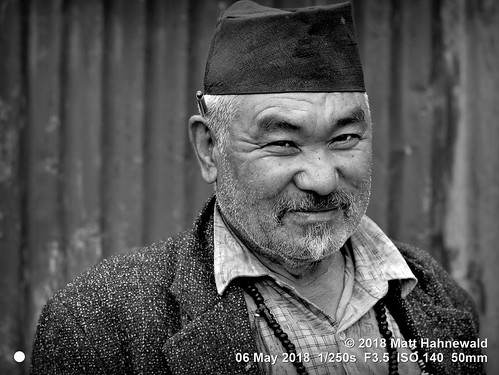 matthahnewaldphotography facingtheworld people character head face eyes expression lookingcamera beard unshaved moustache stubble pencilbehindear headwear cap necklace dhakatopi hat consent concept humanity living work dedication commitment nature travel culture optimism local rural carpenter manegeira helambu nepal asia asian sherpa hyolmo nepali individual oneperson male adult elderly man photo physiognomy nikond3100 primelens nikkorafs50mmf18g 50mm 4x3 horizontal street portrait closeup headshot threequarterview outdoor village workshop mono blackandwhite monochrome greyscale vignette posing overweight clarity respect