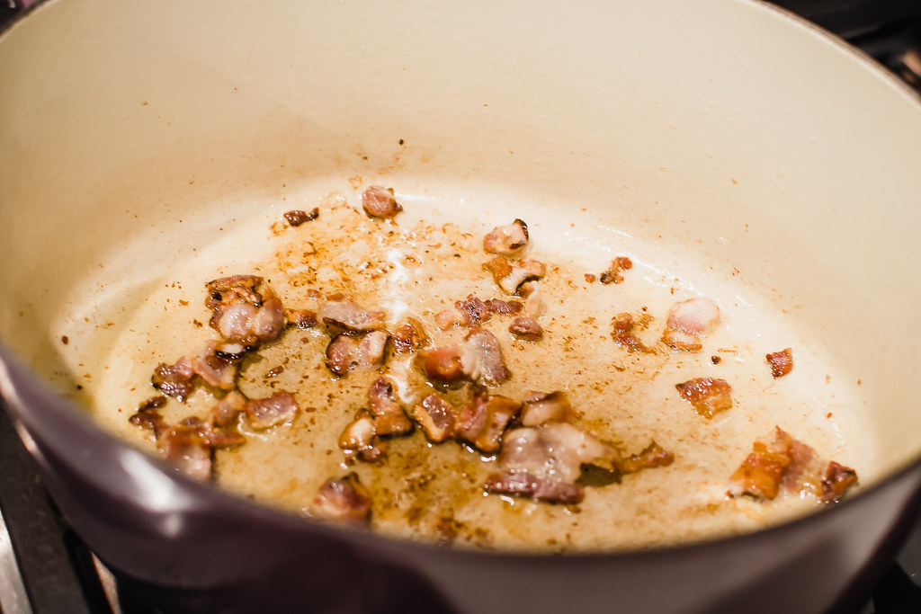 Begin the coq au vin recipe by heating a dutch oven on medium-high heat and sauteing the bacon in hot butter slowly until lightly browned.