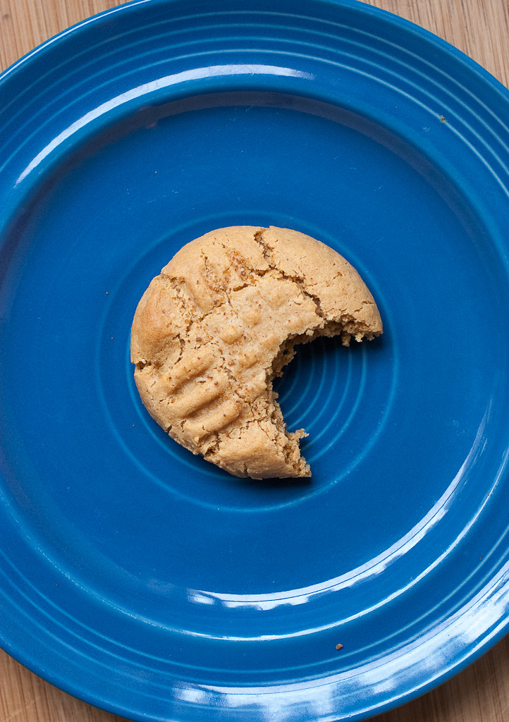 coconut peanut butter cookie with a bite taken out of it on a blue plate
