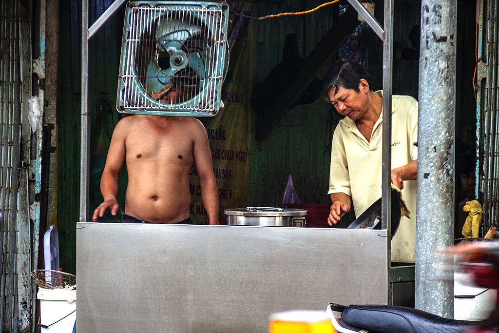 Bare chested man preparing food--Saigon