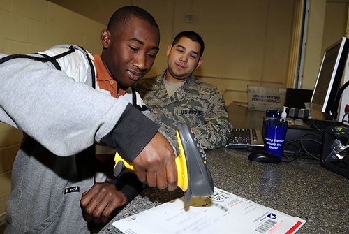 Jared Taylor, 16, scans a package under the guidance of Senior Airman Nolan Luna-Chavez at the RAF Mildenhall post office Aug. 3, 2012