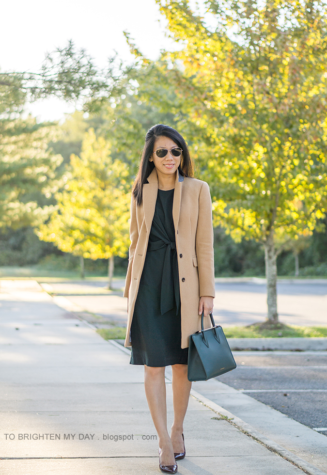 camel long coat, green tie front midi dress, bottle green tote with gold bar, aquamarine ring, burgundy patent pumps