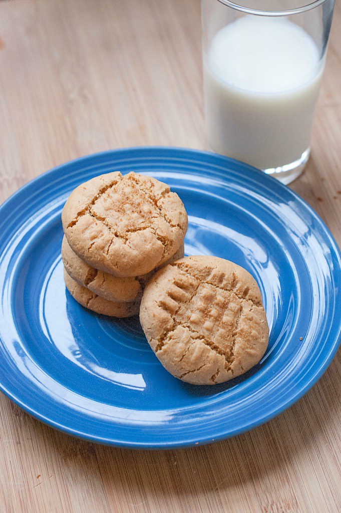 blue plate with stack of tan peanut butter cookies glass of milk