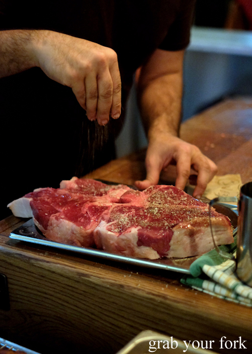 Seasoning bistecca alla fiorentina t-bone steaks with salt and pepper at Bistecca Sydney