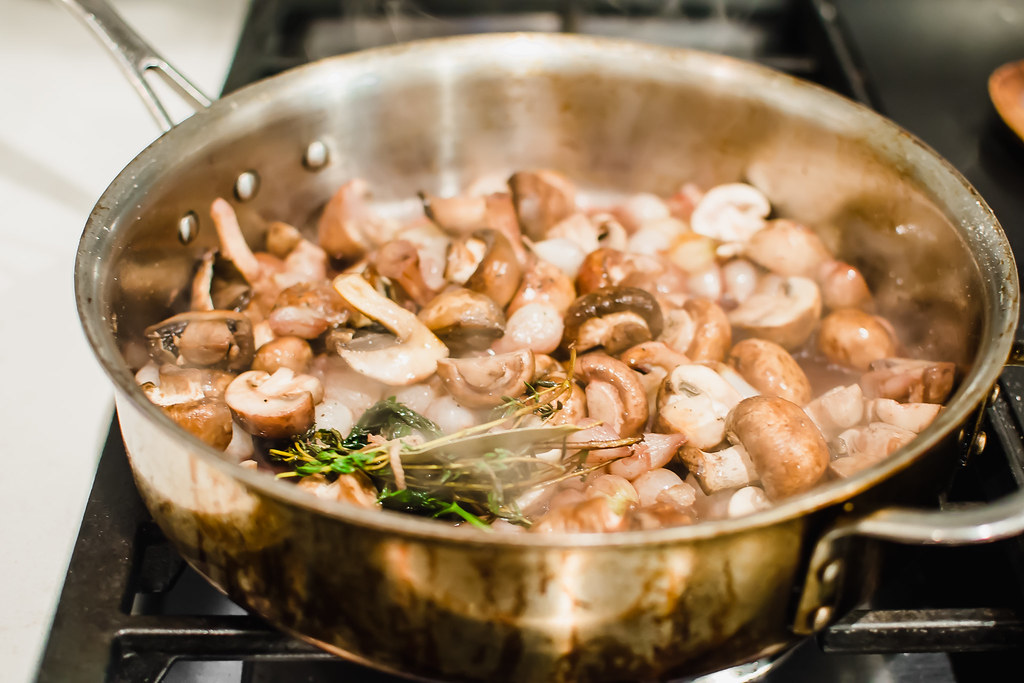 Coq au vin recipe has sautted mushrooms and pearl onions, with fresh herbs, butter and red wine.